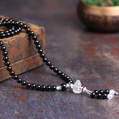 Black agate geometric bead bracelet with 108 beads and number details on a wrist.