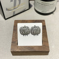 Multi layer metal wire C-ring earrings in gold and silvery colours on a neutral background
