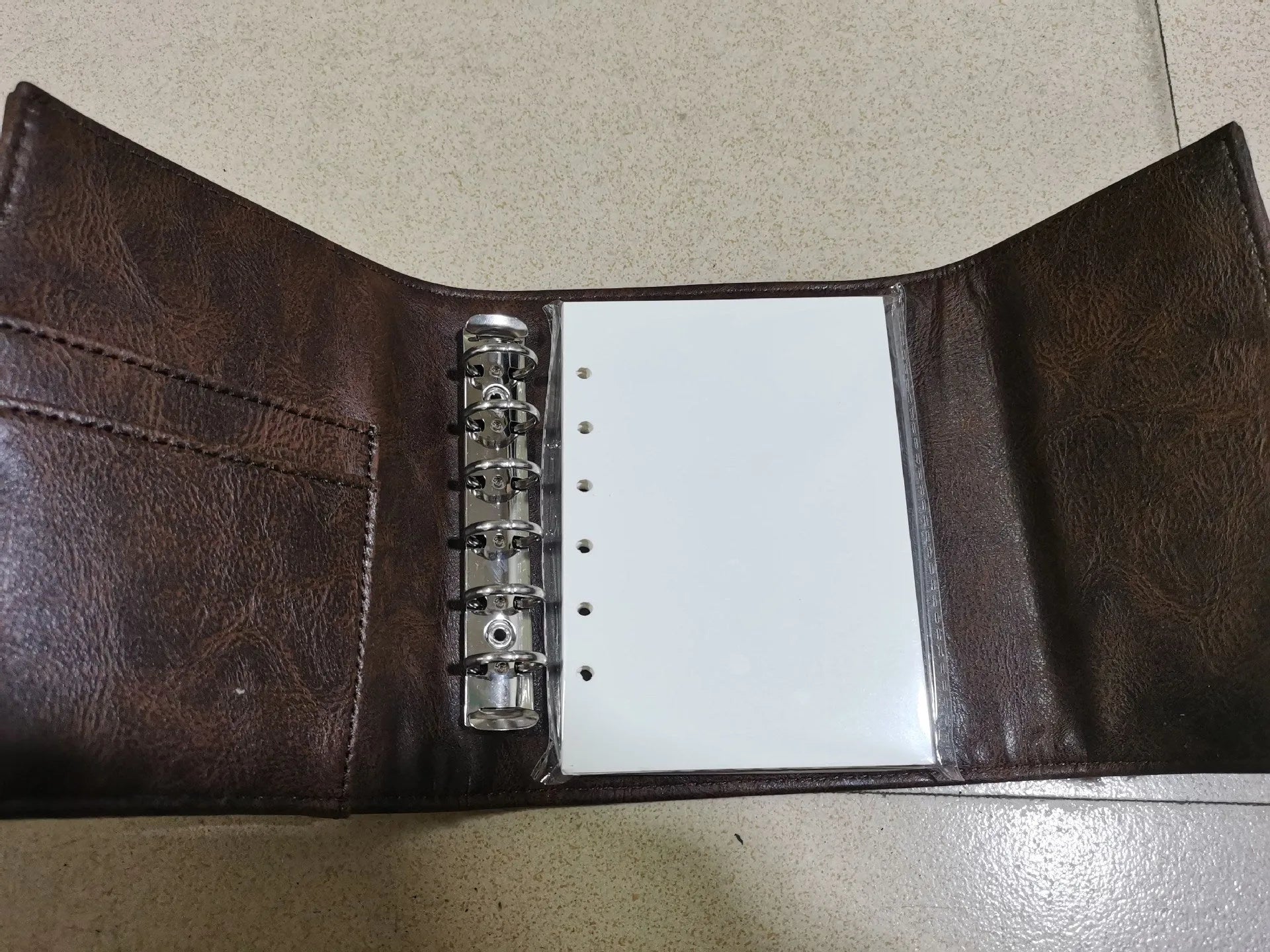 Brown retro-style notebook with a buckle closure and loose-leaf binder binding