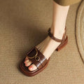 Women's beige leather sandals with a thick rubber sole and a single button closure on the strap.