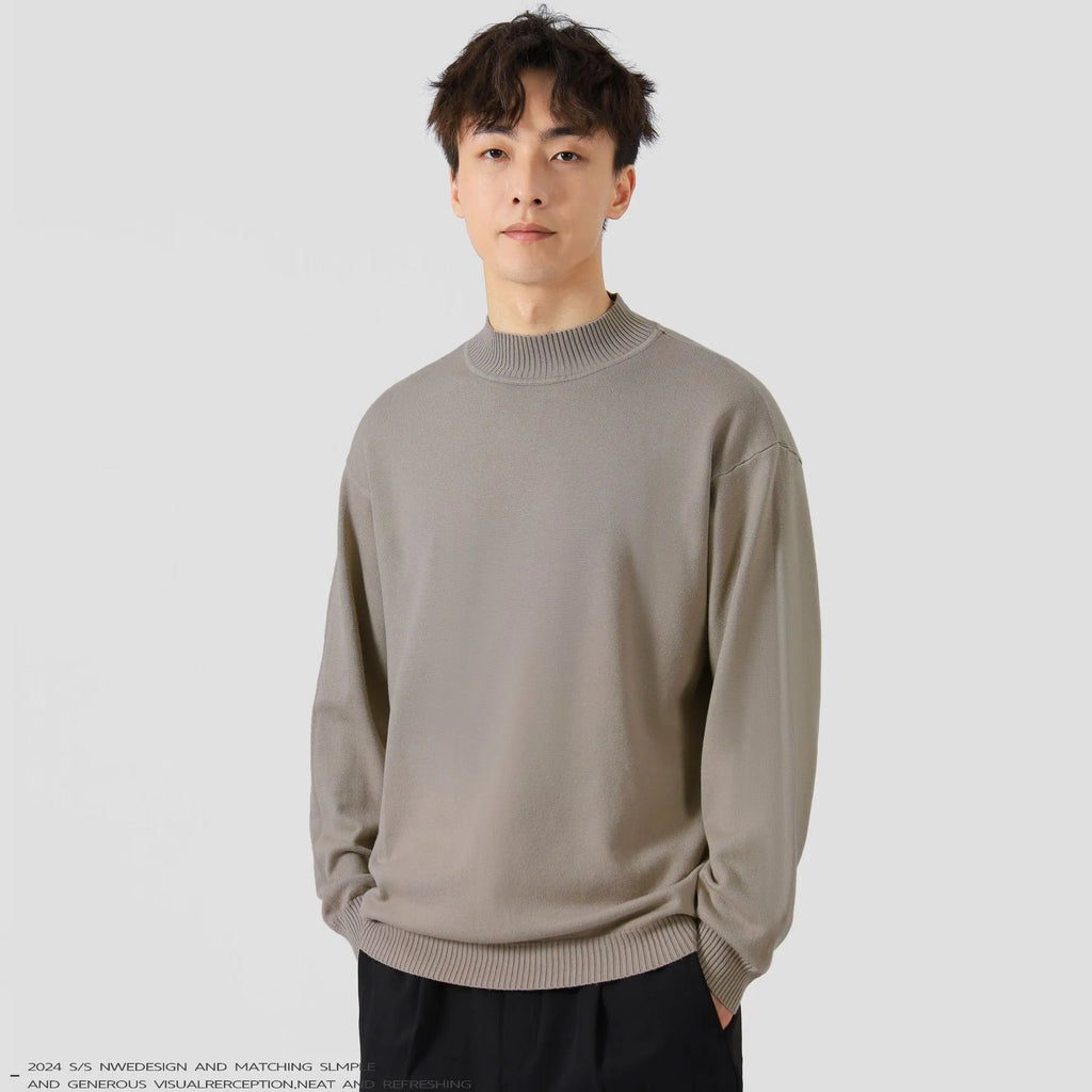 A man wearing a loose-fitting solid colour long sleeve casual pullover sweater.