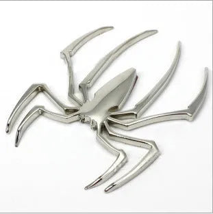 Three-dimensional metal spider bumper sticker in zinc alloy, shown in gold colour, measuring 7 by 5 cm.