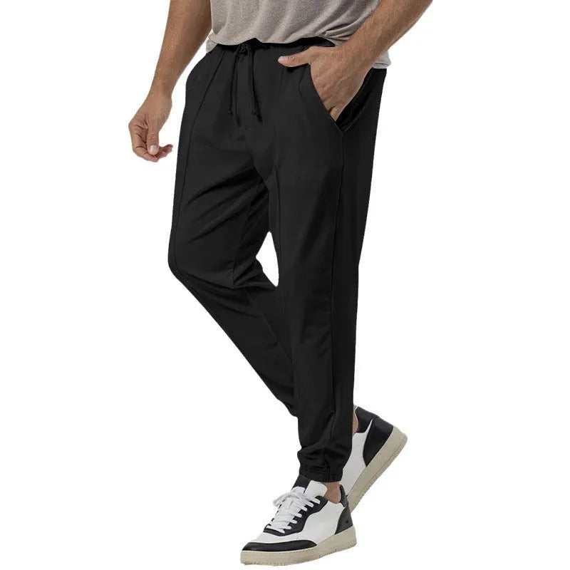 Man wearing grey loose tapered cotton blend track sweatpants, showing straight-leg style.