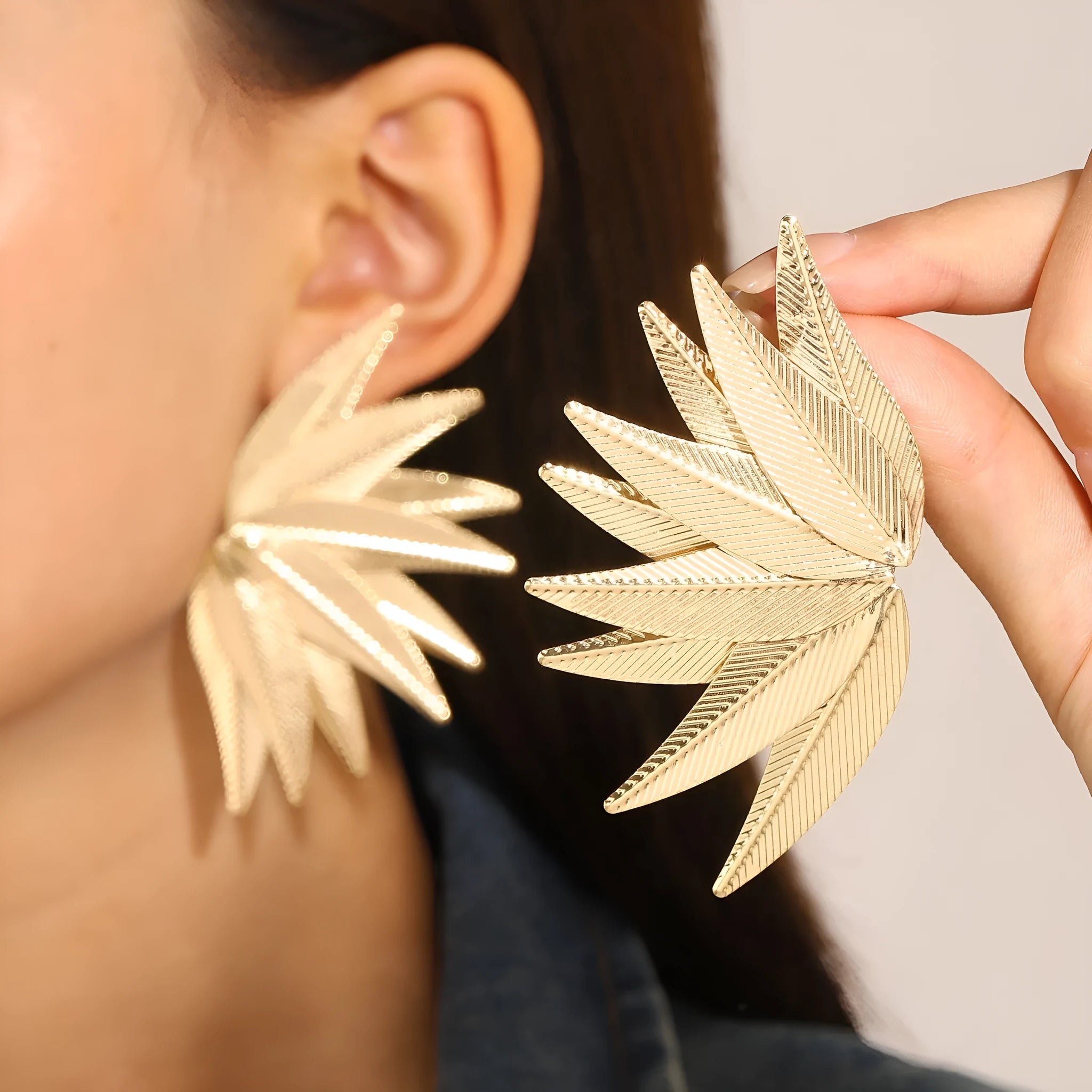 A pair of gold and white alloy patch earrings shaped like leaves.