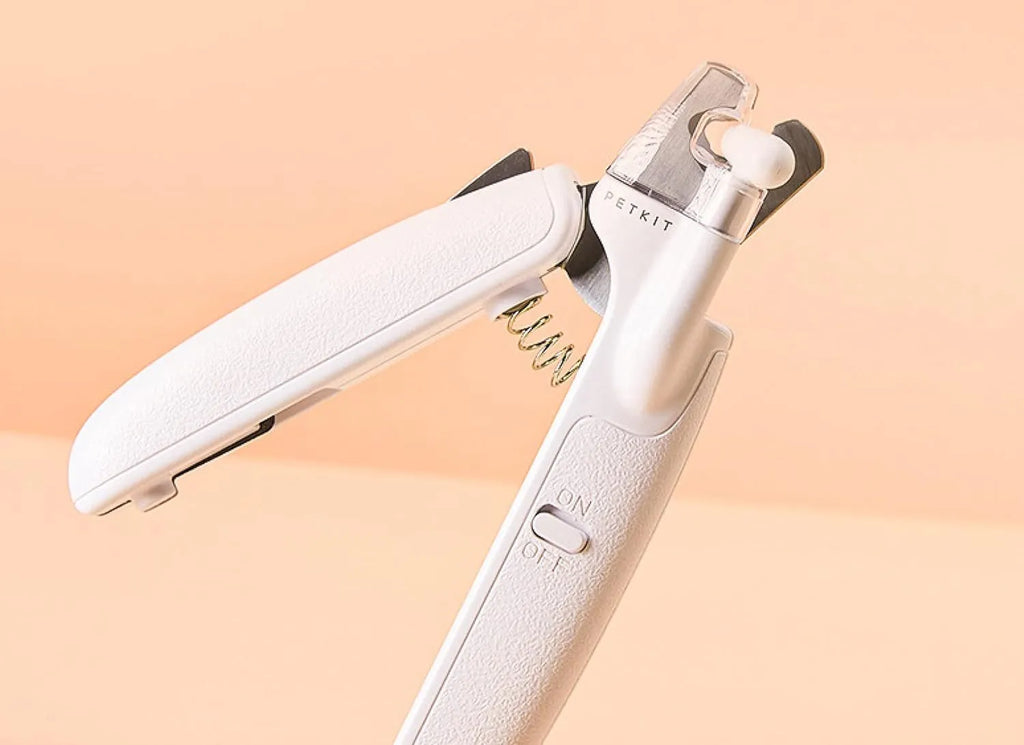 White pet nail clippers with LED light on blade and transparent anti-splash guard, shown with a nail file.