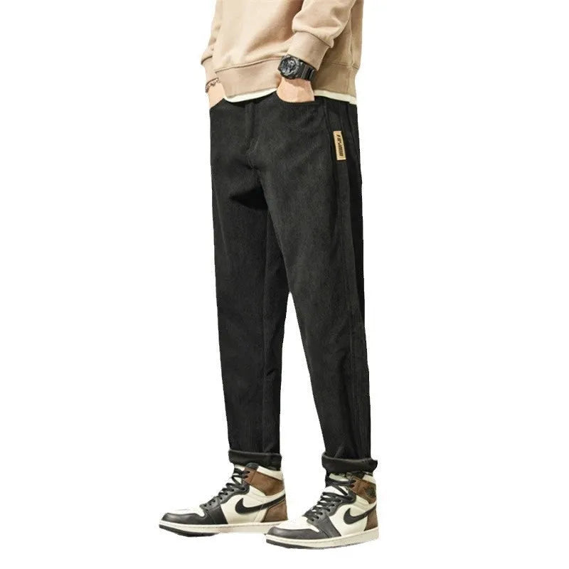 Man wearing tapered straight-leg corduroy trousers in army green, showing mid-rise waist and street style.