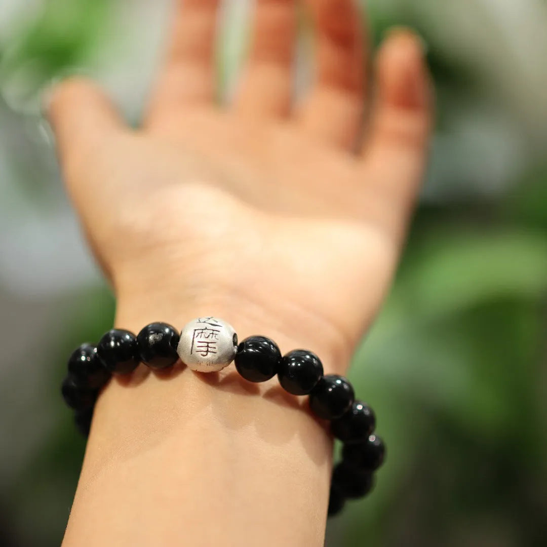 Natural black agate bead bracelet with a sterling silver clasp on a wrist.