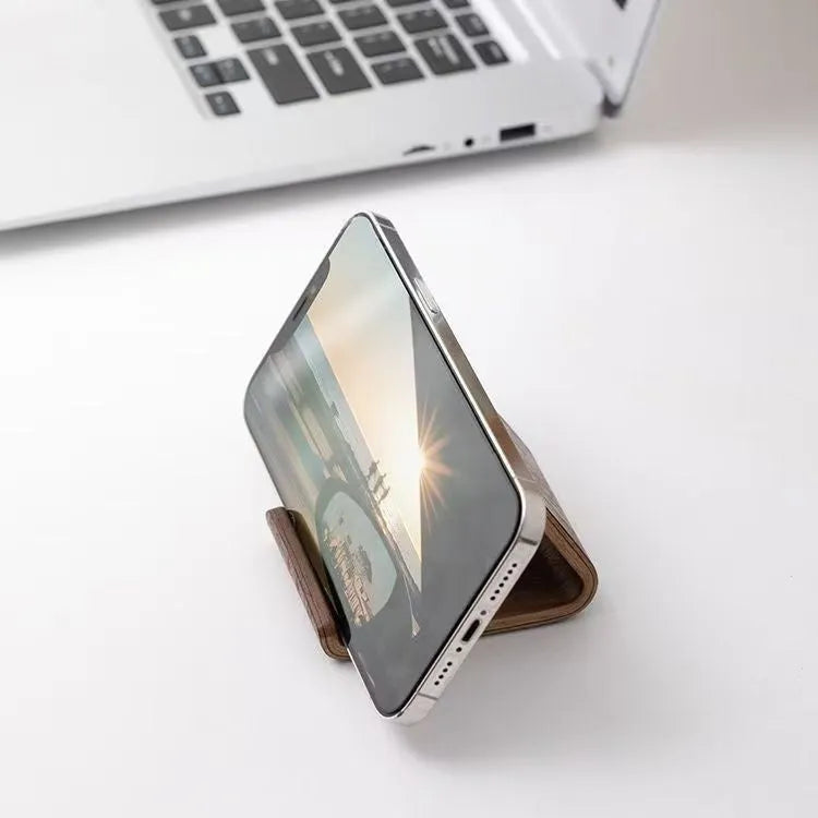 Walnut wood mobile phone bracket holding a smartphone on a wooden desk
