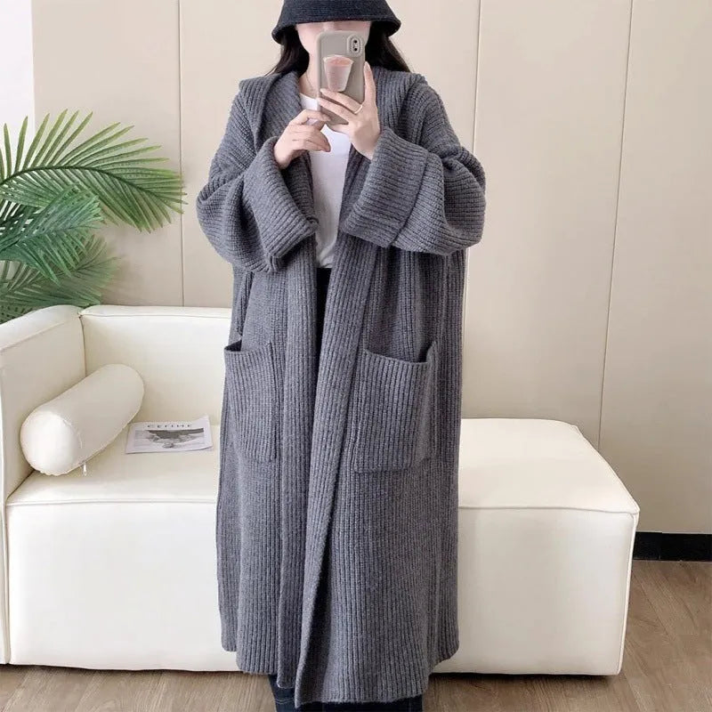 Loose grey hooded sweatshirt cardigan coat with raglan sleeves on a hanger.