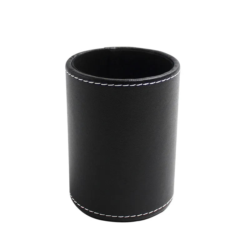 Round black leather pen container on desk holding writing instruments