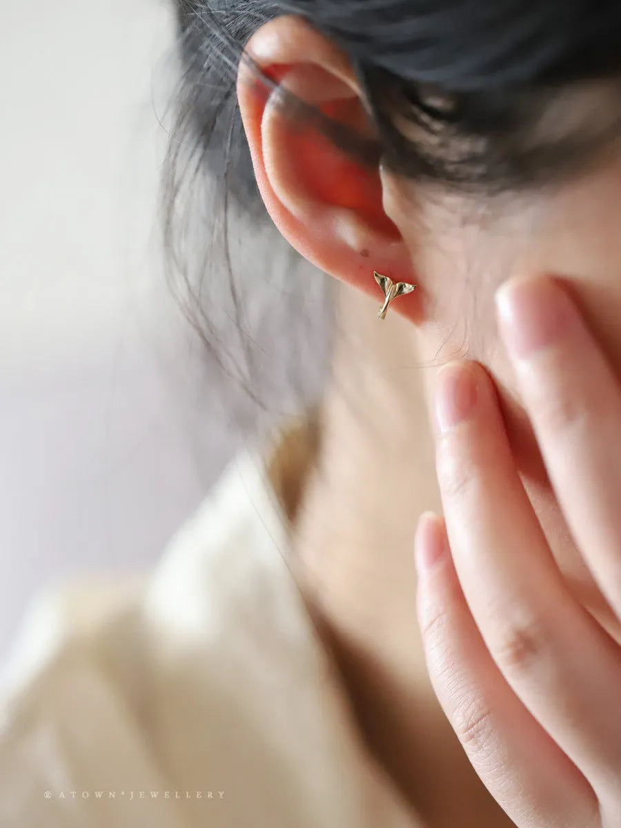 A pair of smooth sterling silver fishtail hoop earrings with a gold plated finish.