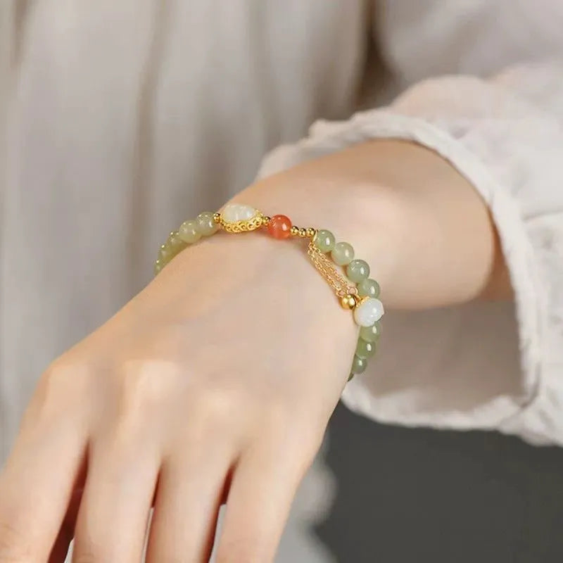 Hand-strung jade bracelet with a gold gourd charm and fu character charm.