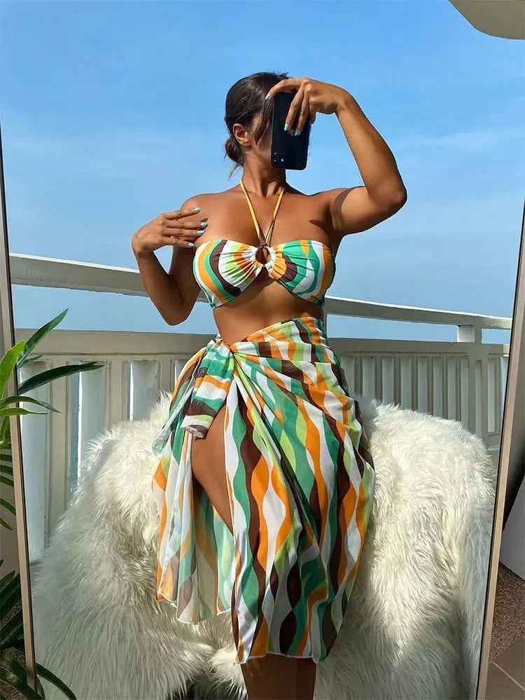 Women's three-piece bikini set with swimsuit top, briefs, and matching printed beach skirt in polyester fabric