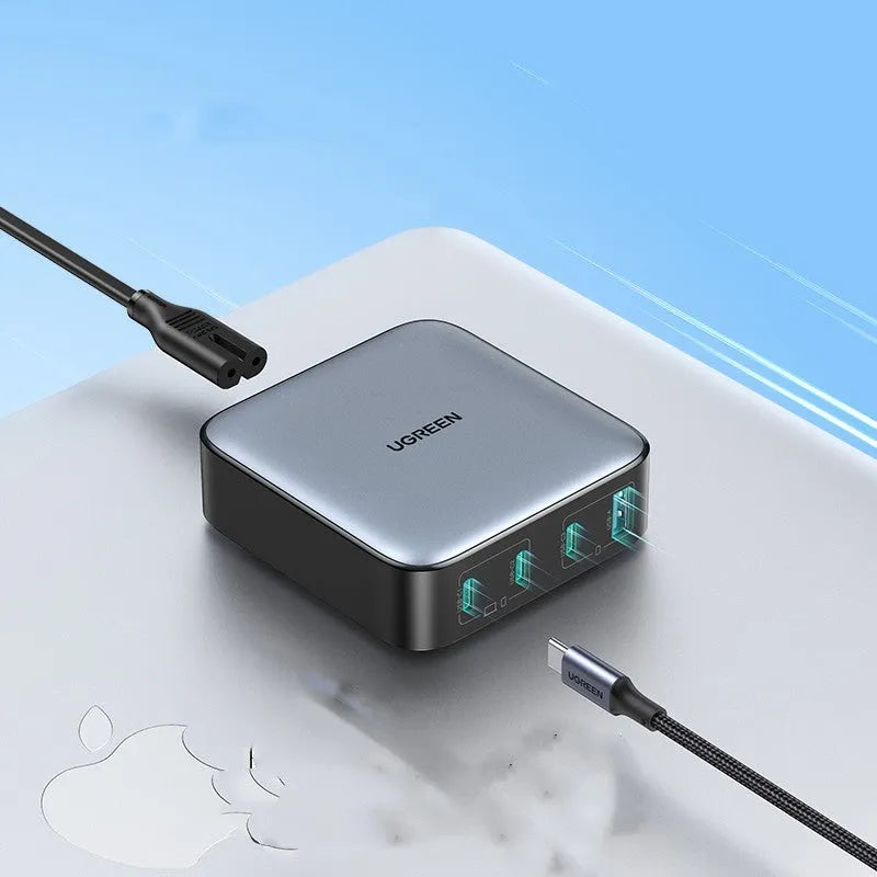 100W Gallium Nitride fast wall charger with USB-C port on a desk next to a laptop.