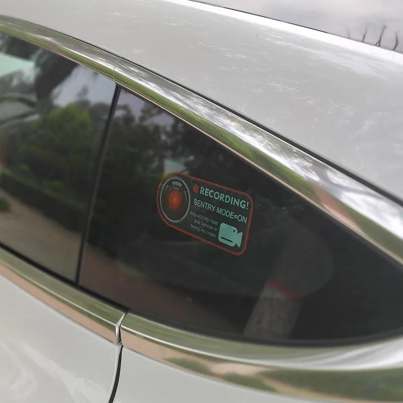 Pair of white rectangular Tesla Sentry Mode warning stickers with black text, 11cm by 5cm.