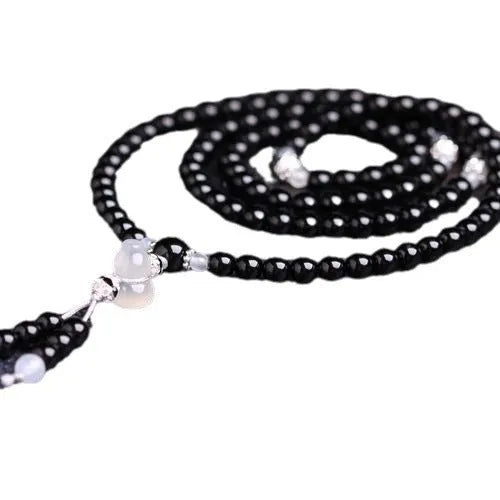 Black agate geometric bead bracelet with 108 beads and number details on a wrist.