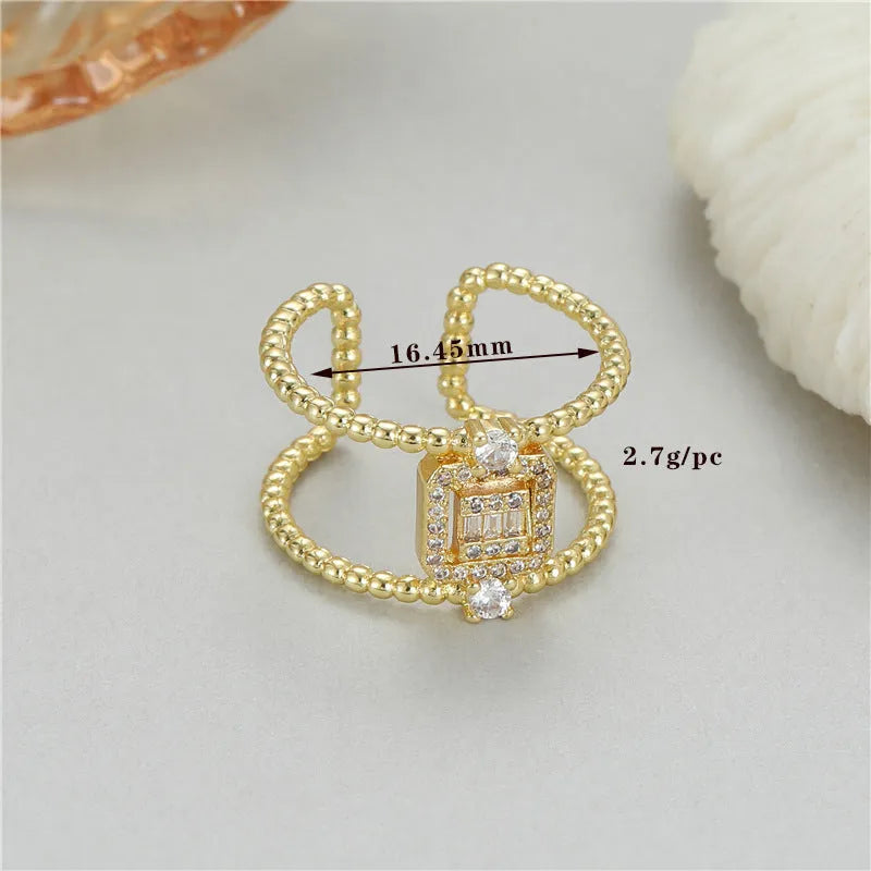 Gold-coloured adjustable open ring with an asymmetric U-shaped design on a finger.