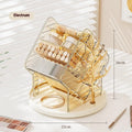 A clear and an amber gold rotating plastic cosmetics storage box on a dressing table.