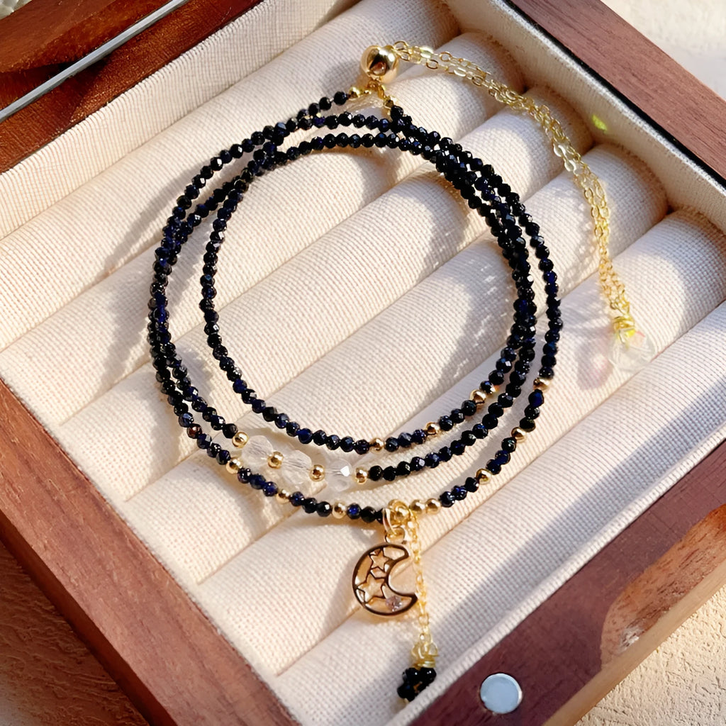 Close-up of a women's multi-layer bracelet with three blue gold sand stone rings on a wrist.