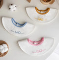Set of three small cotton baby bibs in assorted colours with waterproof layer for milk spill protection