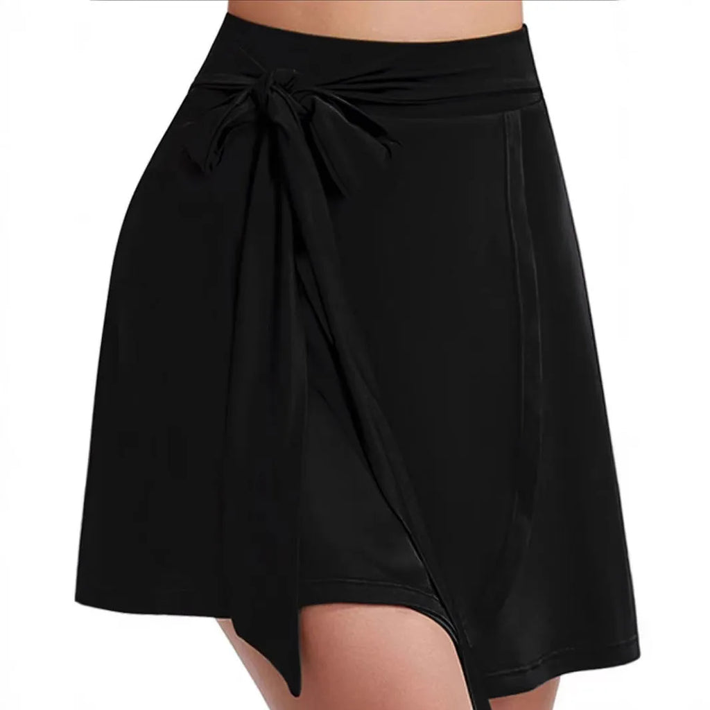 Black thigh-length sports skirt with high waist and built-in shorts, showing shoulder strap detail.