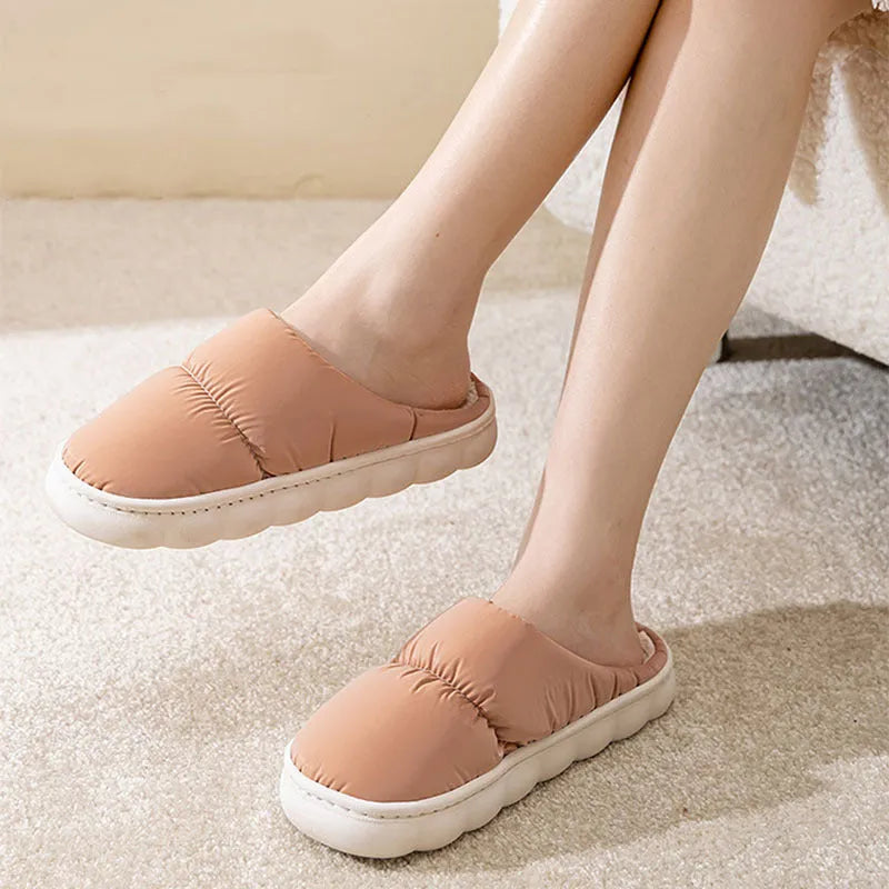 A pair of thick-soled house slippers with an artificial leather upper and plush lining, shown in a choice of colours.