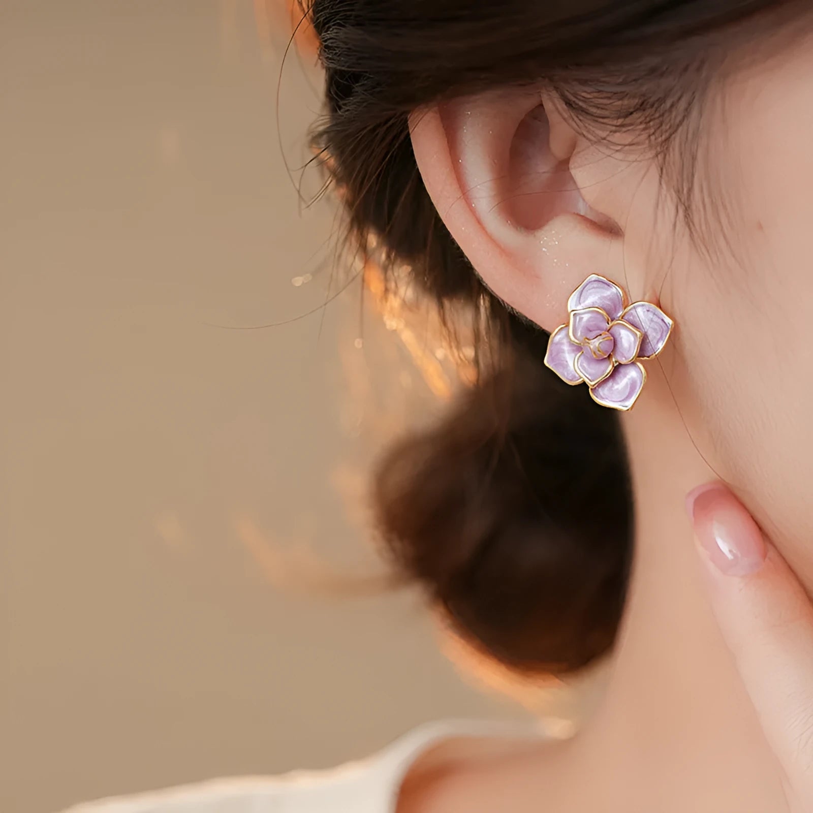 A pair of gold-plated purple floral stud earrings with silver needle details on a white background.