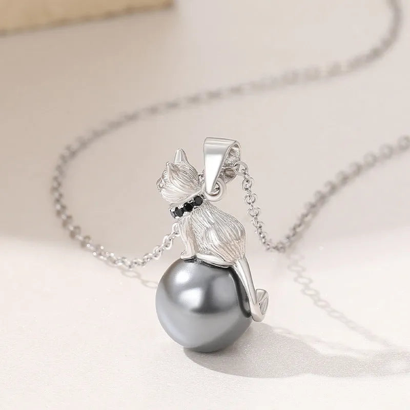 Close-up of a delicate sterling silver cat pendant on a thin clavicle-length chain.