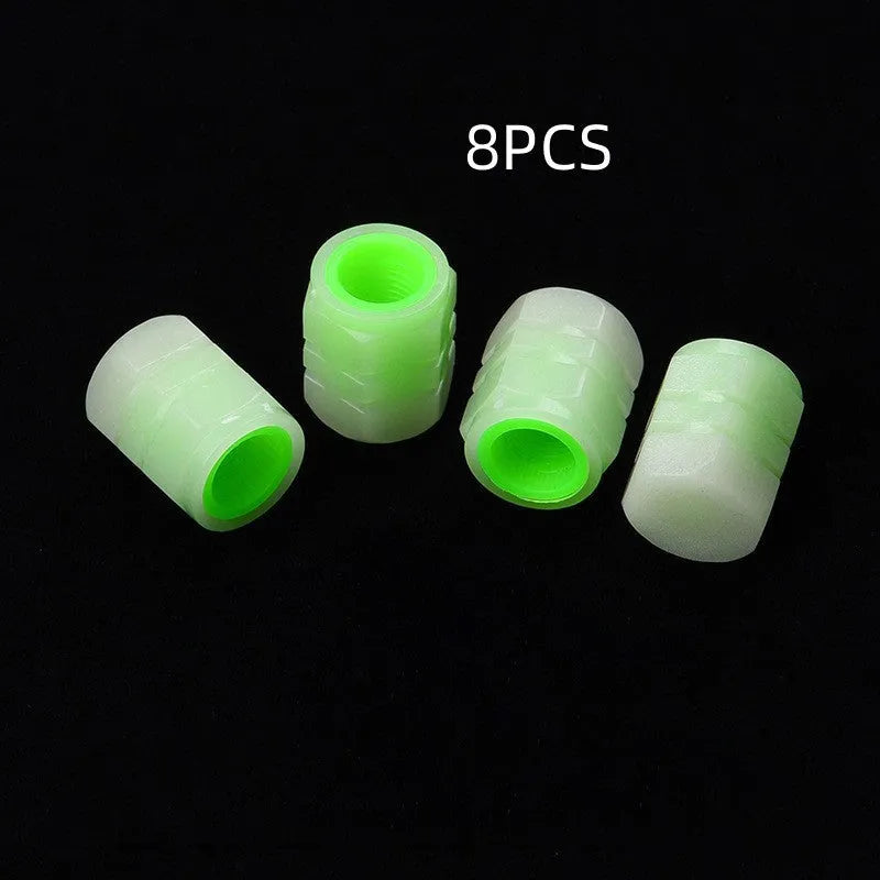 Black rubber luminous car tyre valve cap with glow-in-the-dark tip, shown next to a coin for scale.