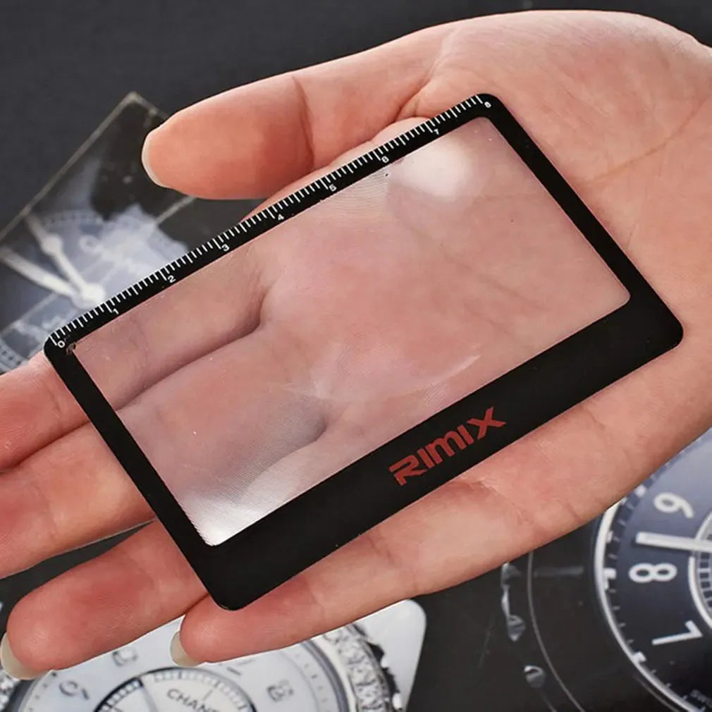 A thin, credit-card sized black plastic magnifier with a Fresnel lens, shown next to a bank card for scale.