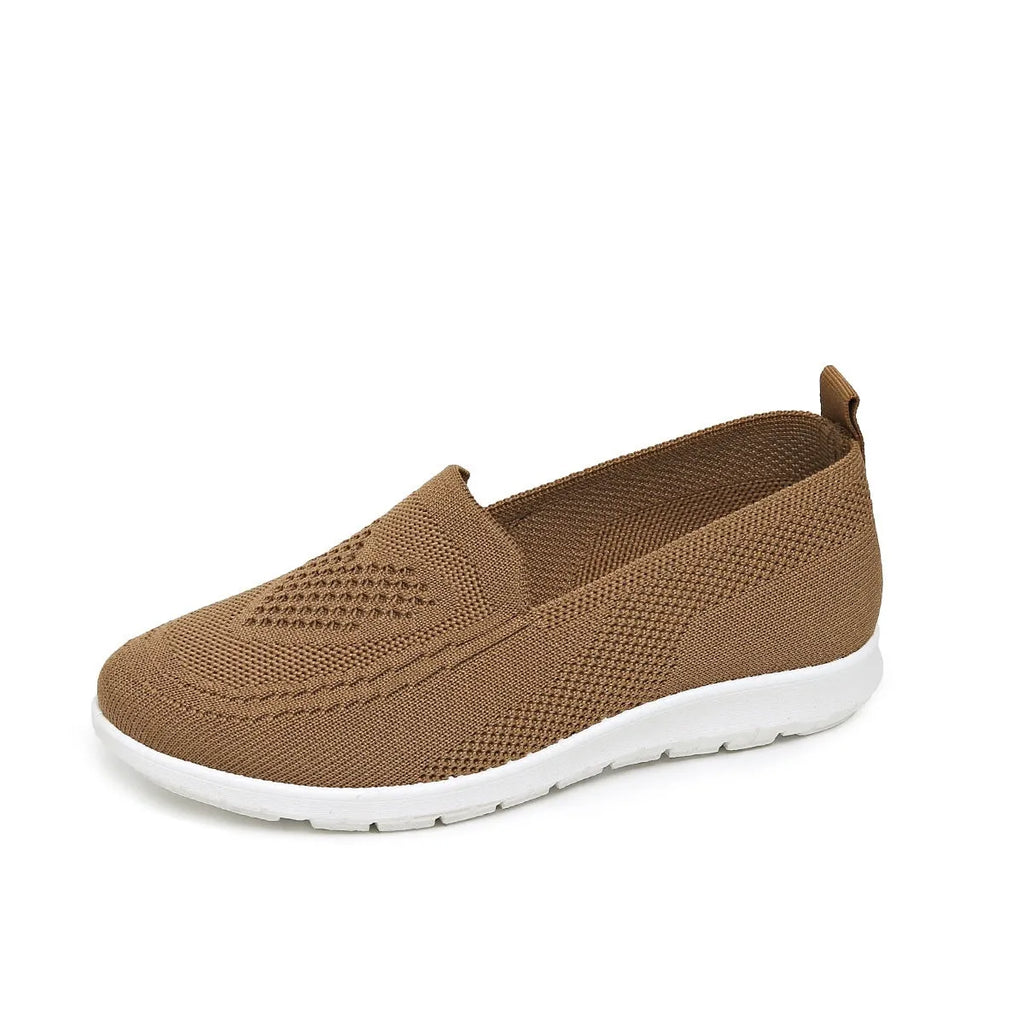 Women's beige canvas slip-on shoe with heart-shaped perforations and a flat sole.