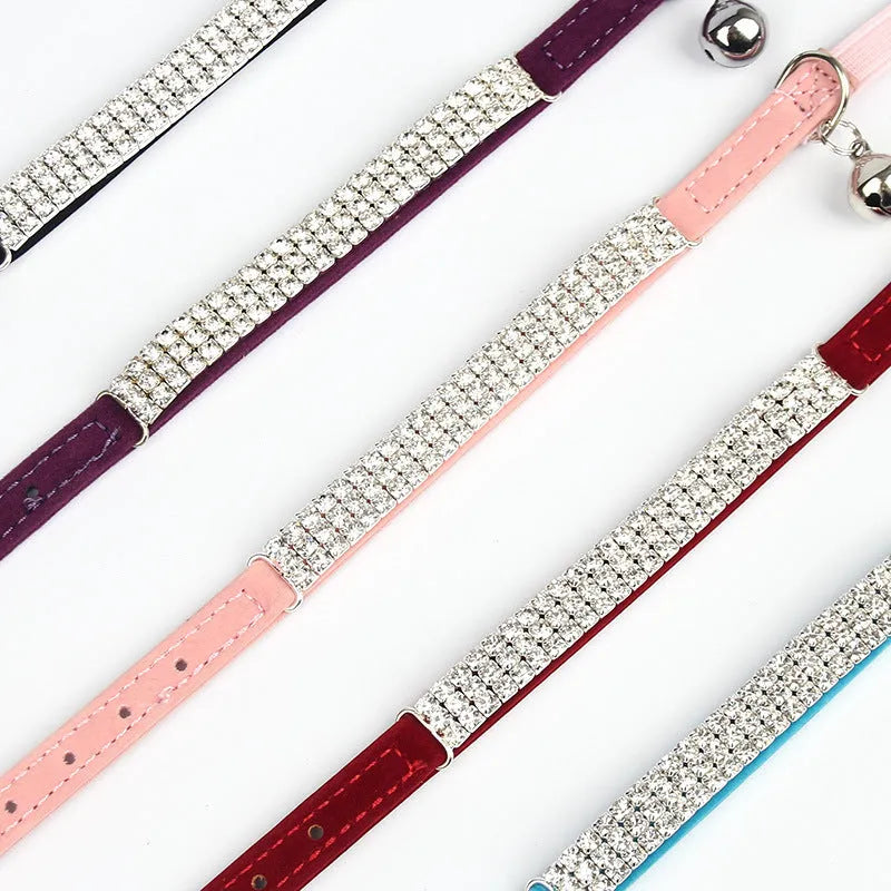Close-up of a red velvet cat collar with rhinestone decoration, showing the adjustable buckle.