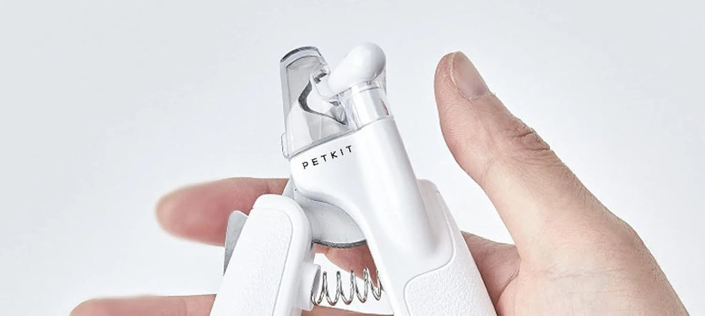White pet nail clippers with LED light on blade and transparent anti-splash guard, shown with a nail file.