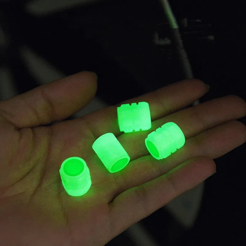Black rubber luminous car tyre valve cap with glow-in-the-dark tip, shown next to a coin for scale.