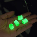 Black rubber luminous car tyre valve cap with glow-in-the-dark tip, shown next to a coin for scale.