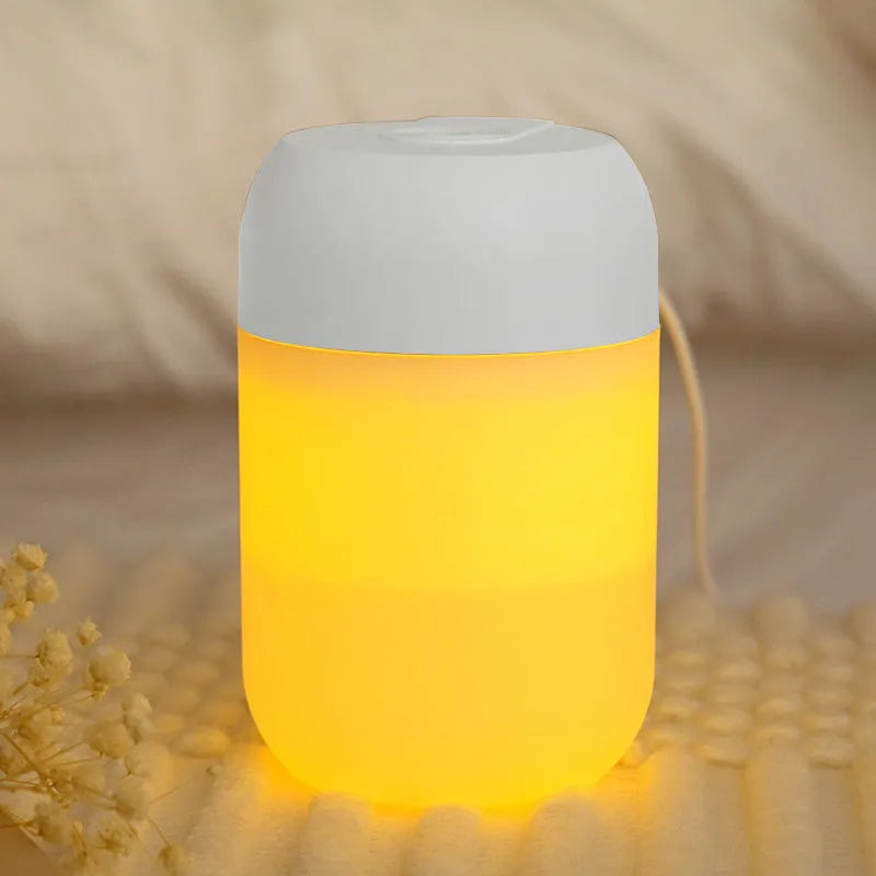 Small white cylindrical USB-powered humidifier with charging cable on a desk.