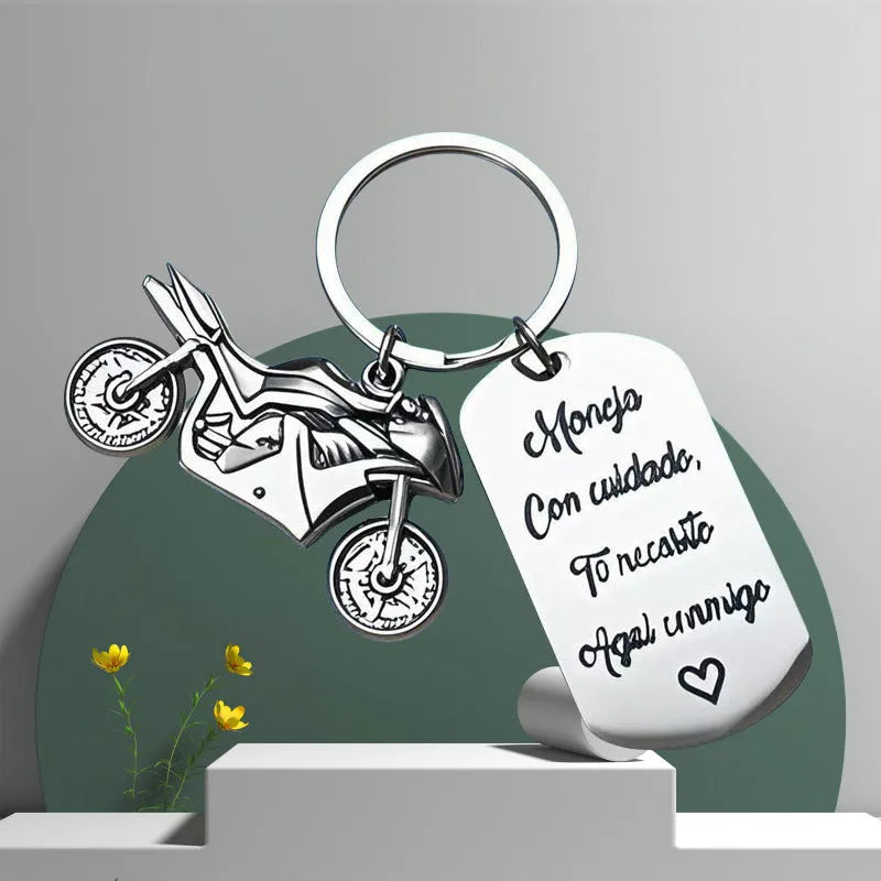 Stainless steel motorcycle keychain with inspirational design, shown with its included flannel storage bag.