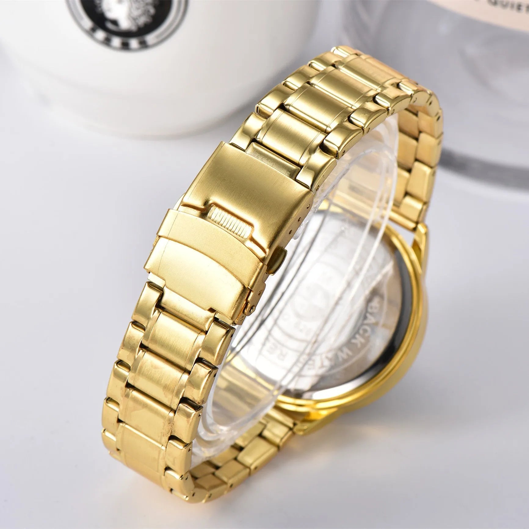 Steering wheel fashion watch with 43mm circular alloy case, stainless steel strap, and pointer display on a light background.