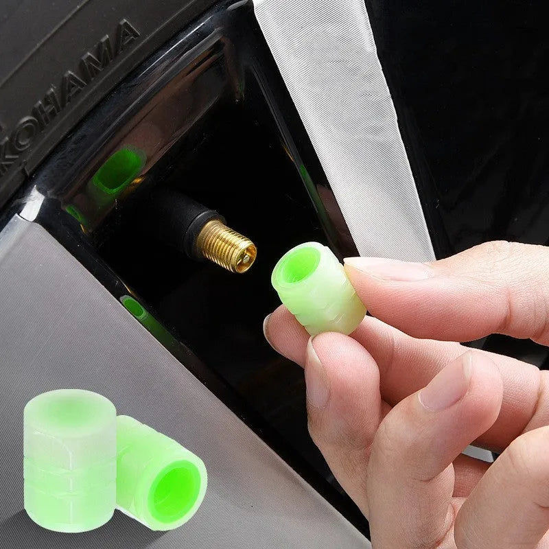 Black rubber luminous car tyre valve cap with glow-in-the-dark tip, shown next to a coin for scale.