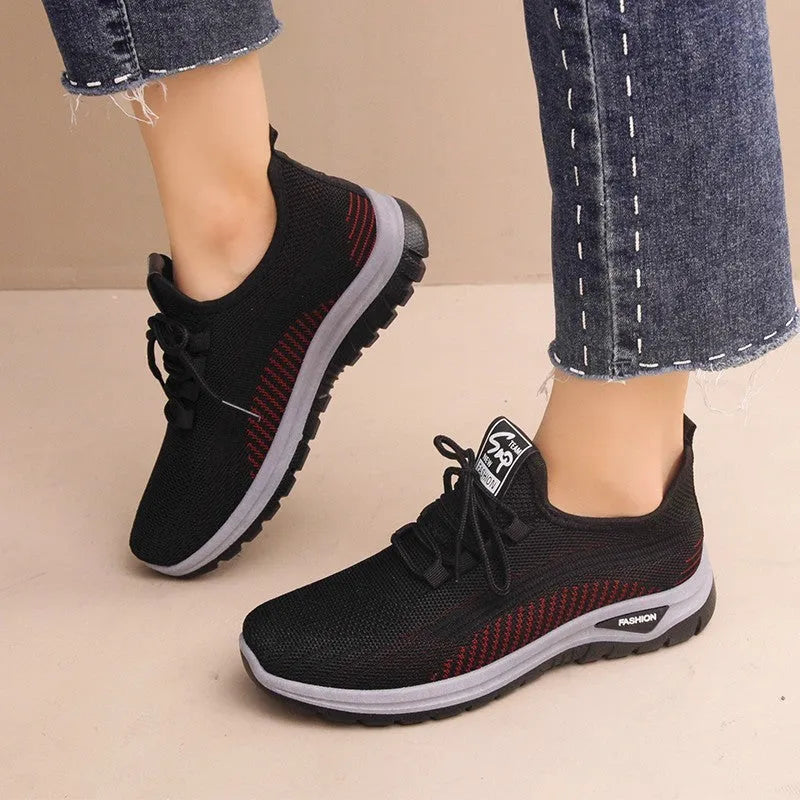 Women's low top sneakers in black with mesh panels, cross straps, and a round toe head on a rubber sole.