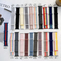 Woven fabric Apple Watch replacement strap shown in multiple colour options including reflective finishes.