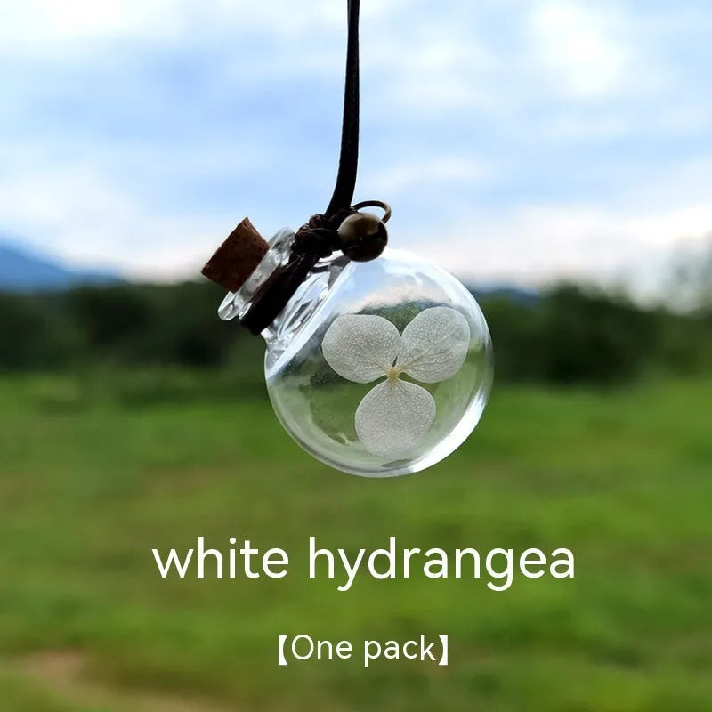 Glass car perfume pendant with preserved flowers inside, shown in light pink hydrangea colour
