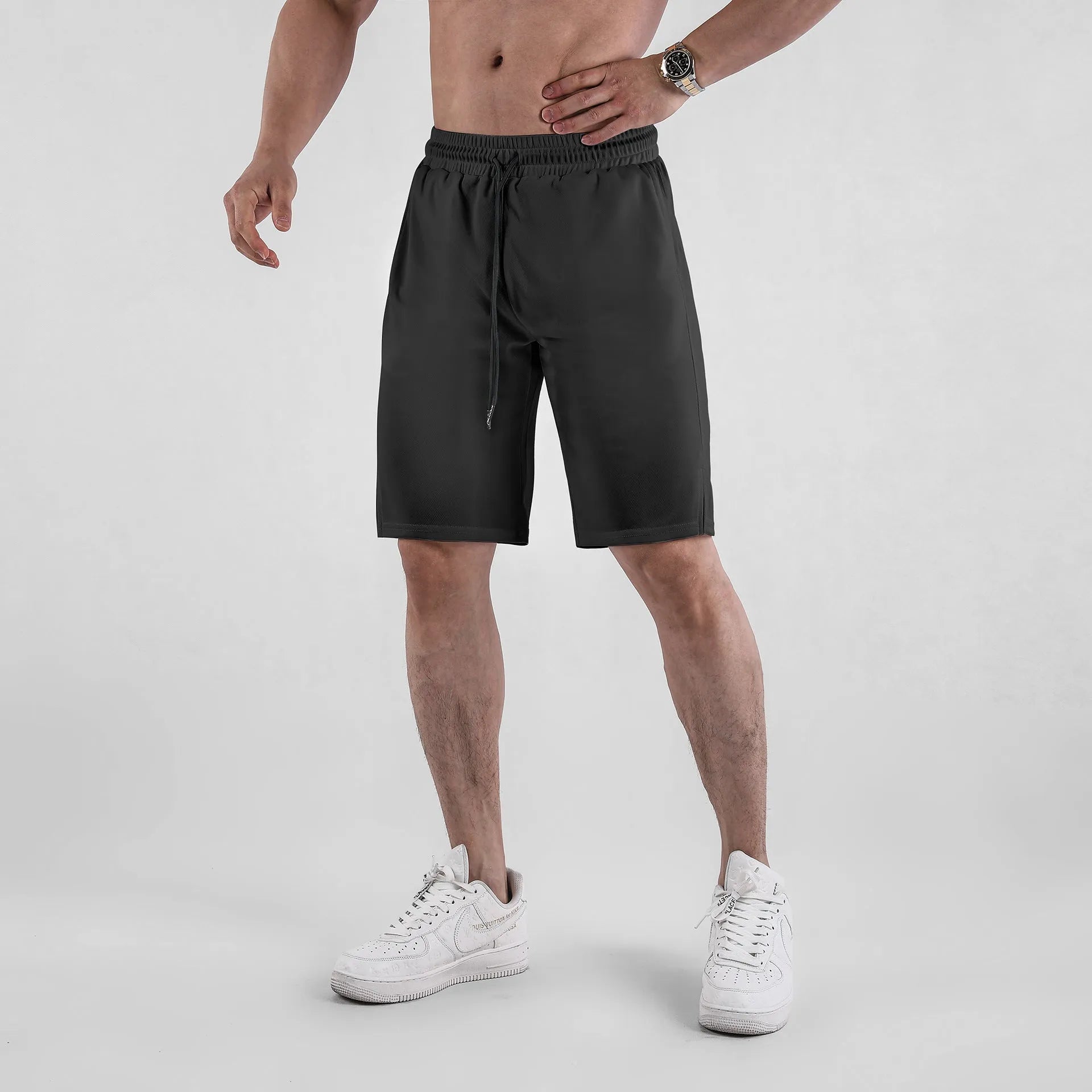 Men's black quick-drying mesh fitness shorts with an elastic waistband, shown in a loose, capri-length style.