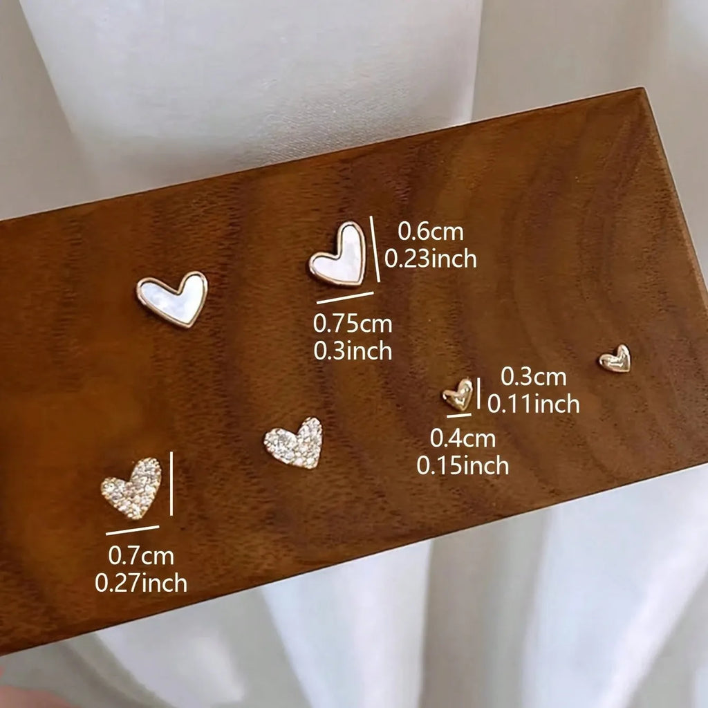 Three pairs of heart-shaped alloy earrings with love motif in gold, black, black and white, and pink colours.
