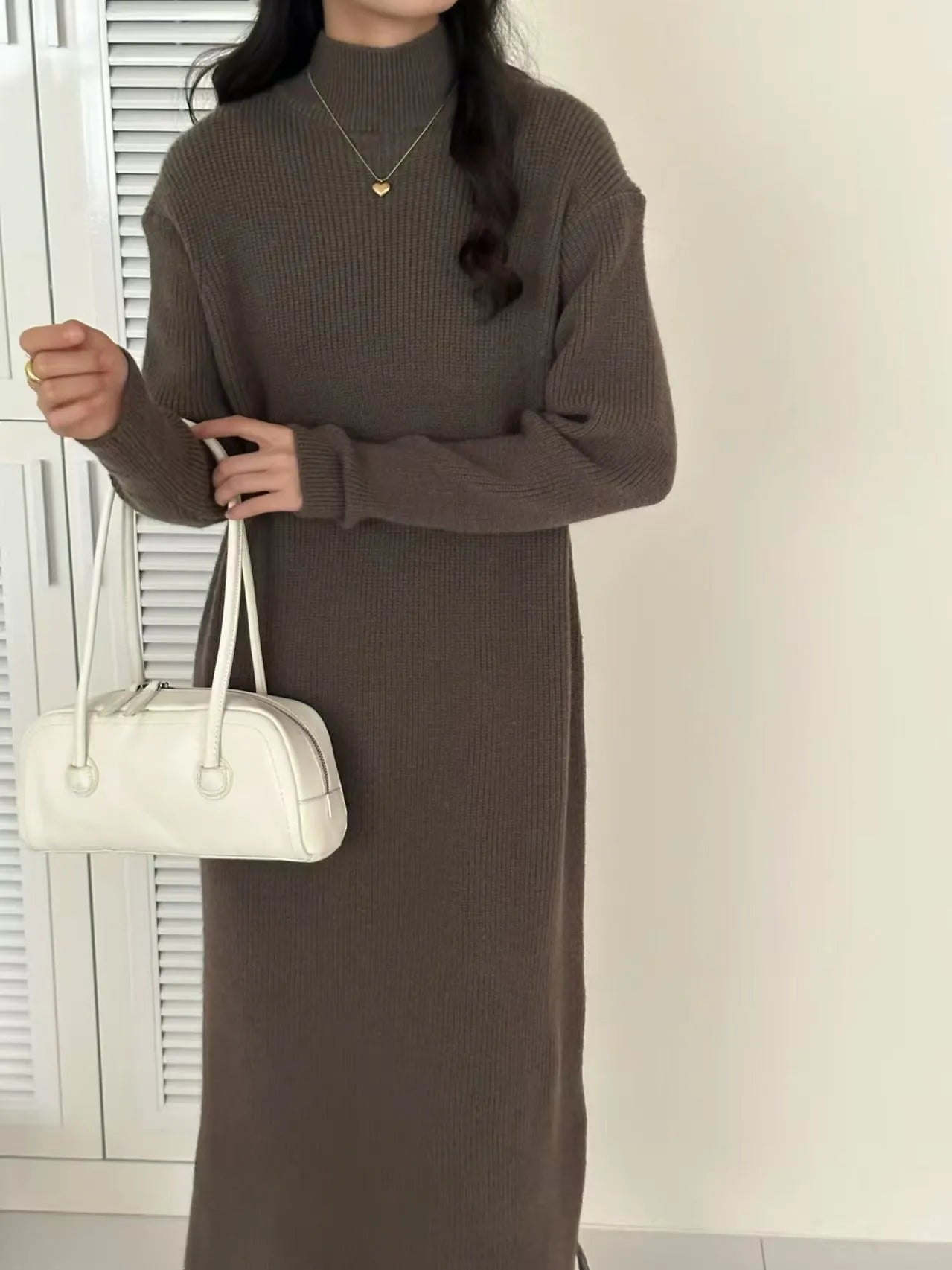 Woman wearing a milky white half turtleneck acrylic knit dress with a high waist and overknee A-line skirt.