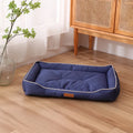 Grey waterproof dog sofa bed with raised edges, shown in a living room setting.