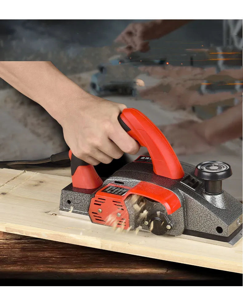 Red desktop electric wood planer with aluminium body on a workbench.