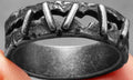 Stainless steel double ring with punk stitching style design on a finger.
