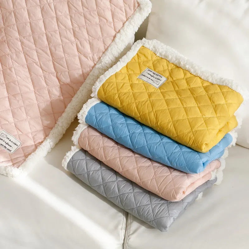 Quilted blue terry cloth pet blanket for cats on a white background, showing size scale.