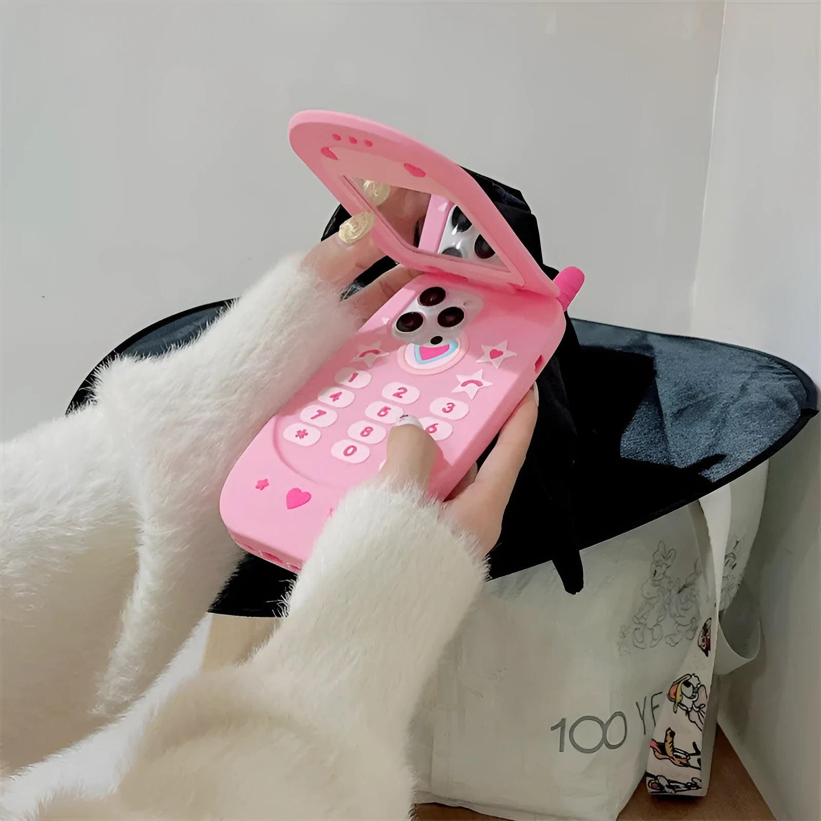 Pink silicone iPhone case with a flip-open mirror cover on a table.